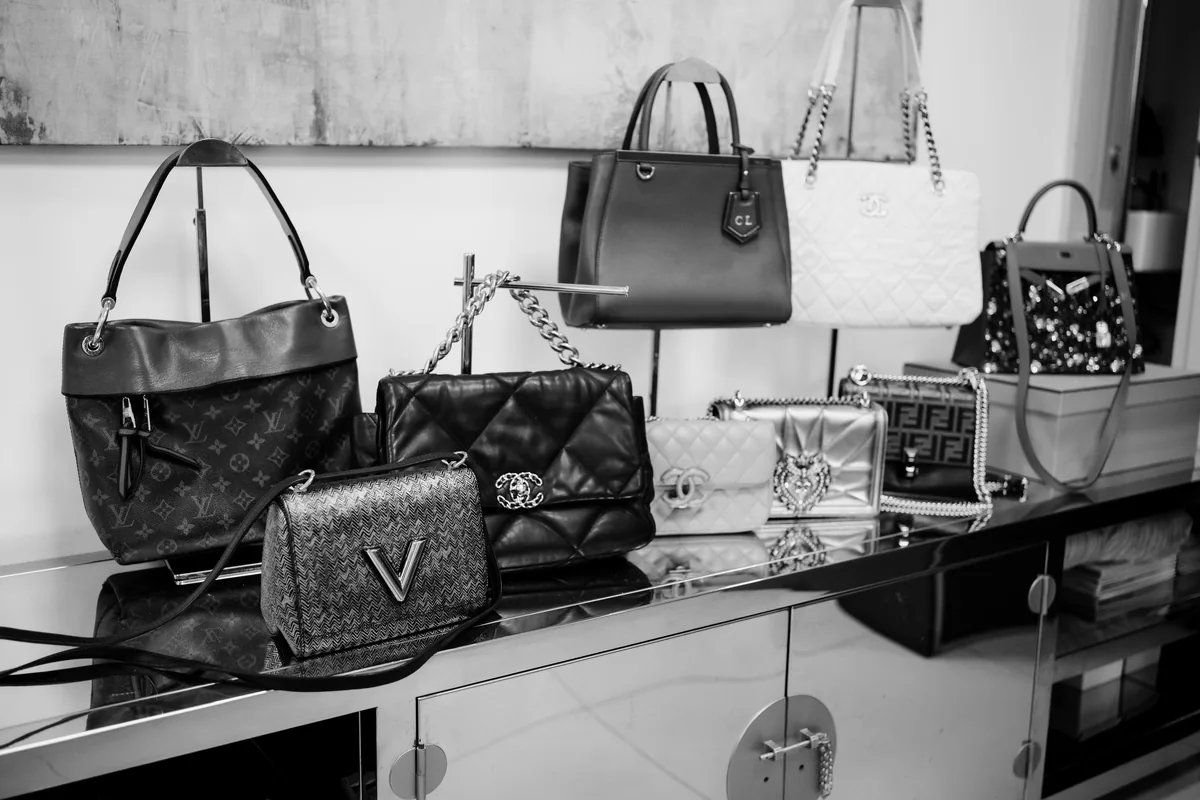 Bolsas Louis Vuitton e Chanel em preto e branco sobre bancada espelhada