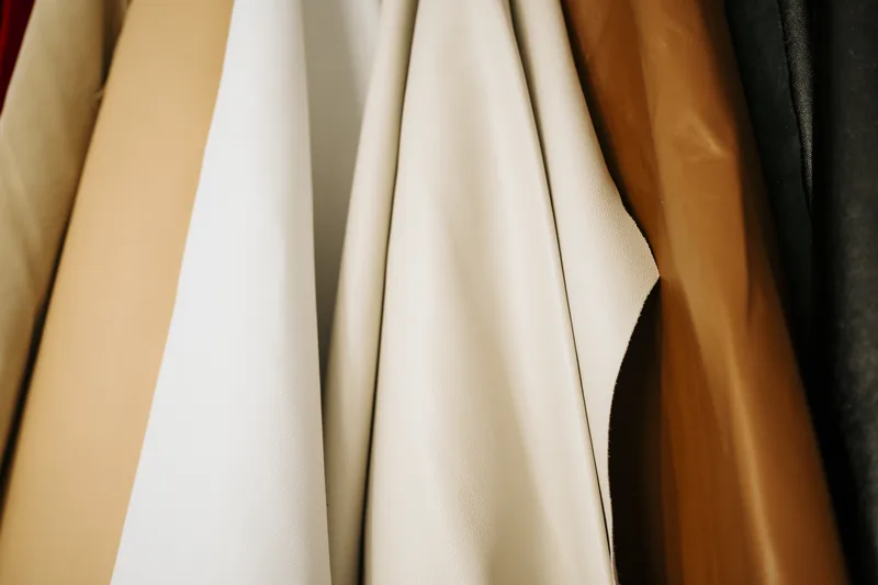 Couros em tons de nude, branco, caramelo e preto pendurados no ateliê