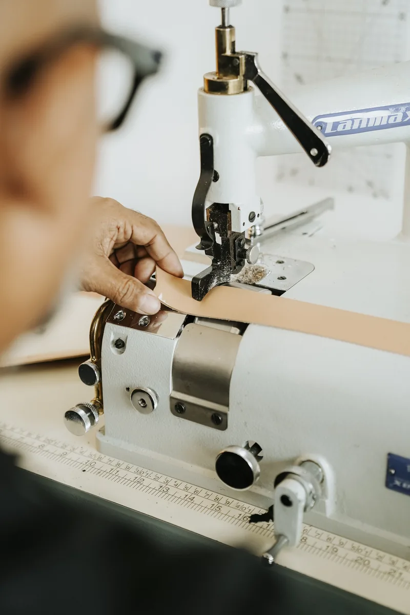 Artesão preparando uma tira de couro em máquina de chanfrar